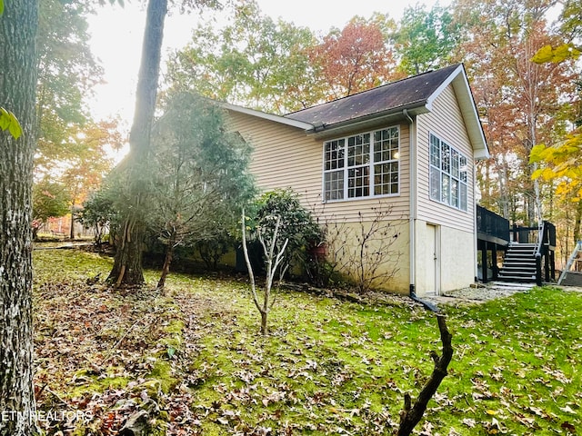 view of side of home with a wooden deck and a yard