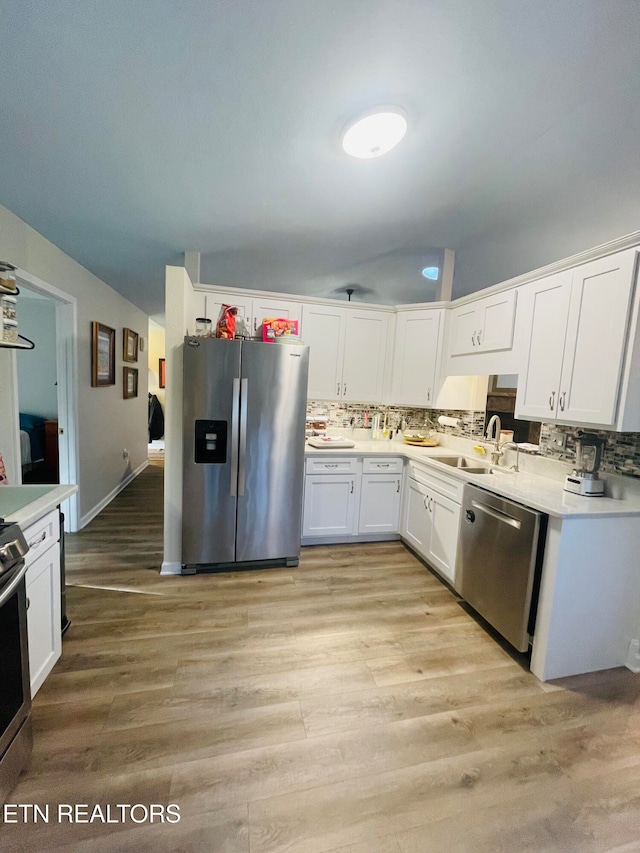 kitchen with white cabinets, appliances with stainless steel finishes, light hardwood / wood-style flooring, and sink