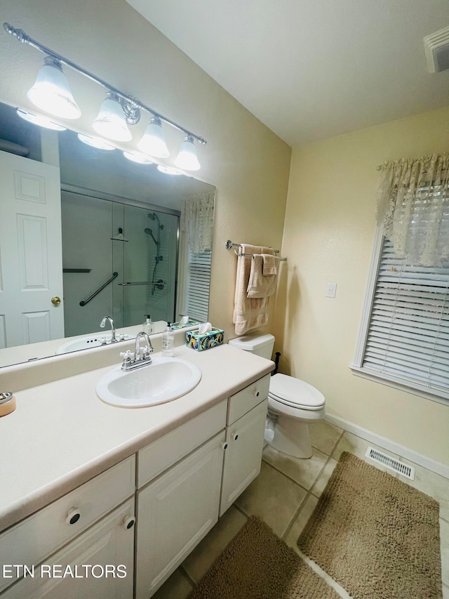 bathroom with a shower with shower door, toilet, vanity, and tile patterned flooring