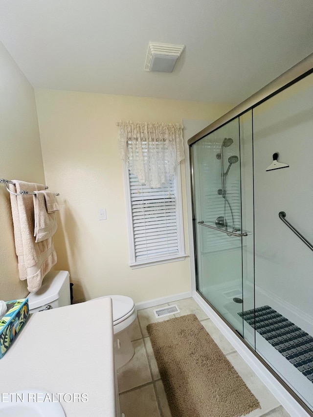 bathroom with toilet, tile patterned floors, and an enclosed shower