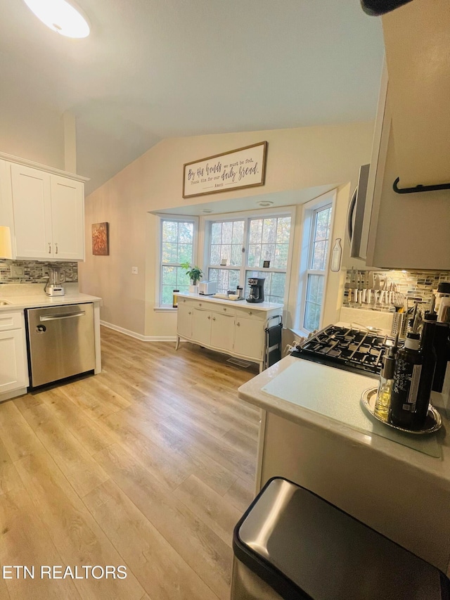 kitchen featuring lofted ceiling, decorative backsplash, white cabinetry, light wood-type flooring, and appliances with stainless steel finishes