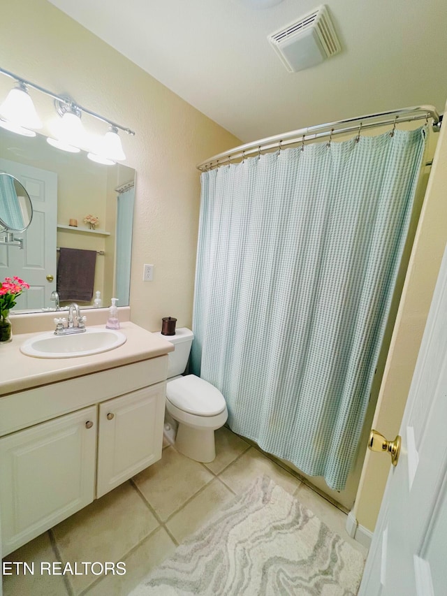 bathroom with toilet, vanity, tile patterned floors, and walk in shower