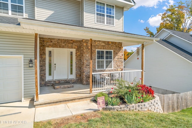 view of exterior entry with covered porch and a garage