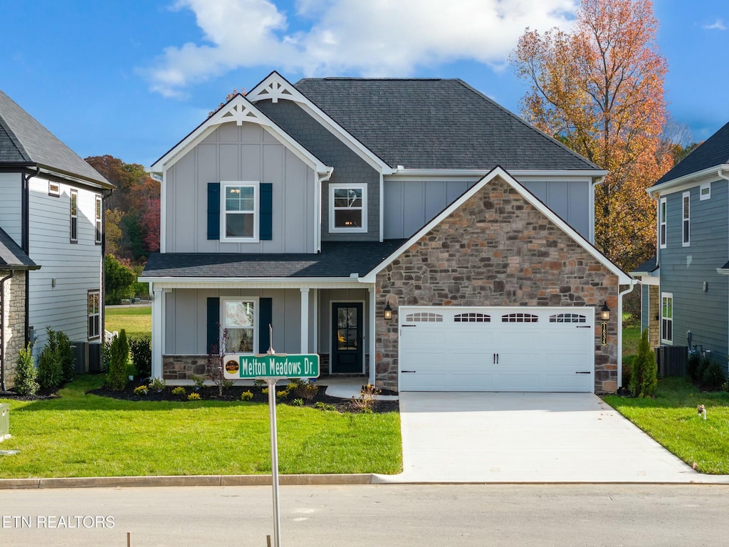 craftsman inspired home featuring a front yard, a garage, and central AC unit