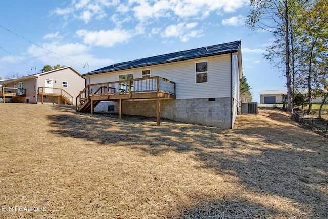 back of house with central air condition unit, a deck, and a lawn