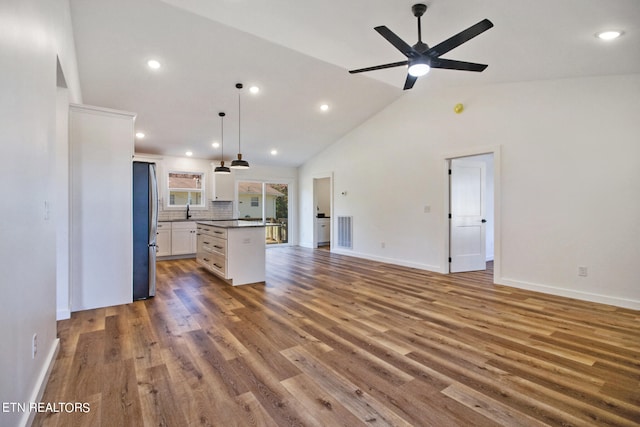 kitchen featuring a kitchen island, wood-type flooring, stainless steel fridge, decorative light fixtures, and white cabinetry