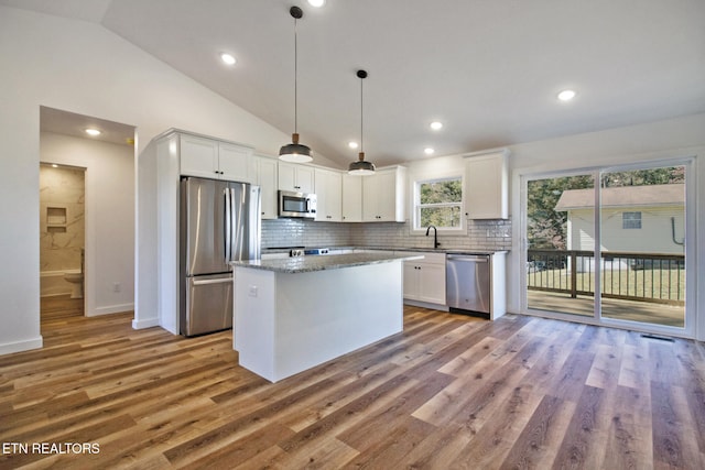 kitchen featuring white cabinets, stainless steel appliances, lofted ceiling, and hanging light fixtures