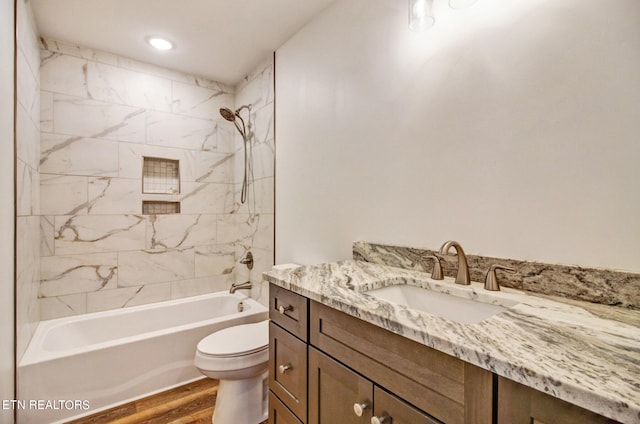 full bathroom featuring toilet, tiled shower / bath, hardwood / wood-style floors, and vanity