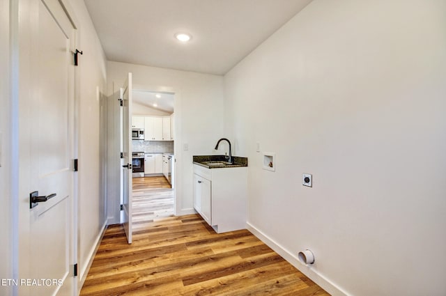 clothes washing area with hookup for a washing machine, sink, electric dryer hookup, cabinets, and light hardwood / wood-style flooring