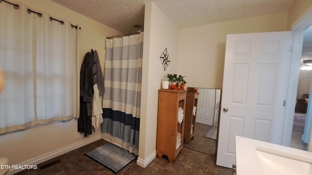 bathroom with vanity, shower / tub combo with curtain, and a textured ceiling