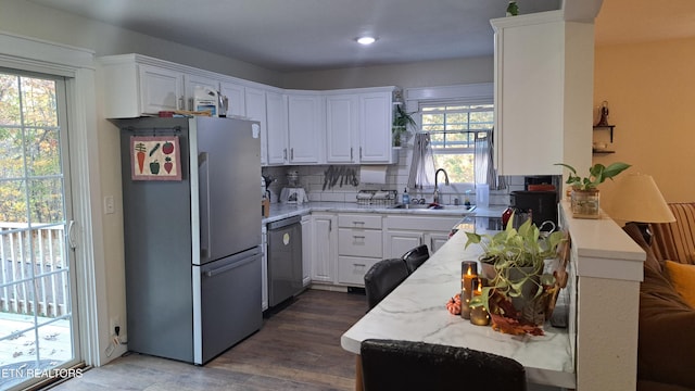 kitchen with white cabinetry, sink, dark hardwood / wood-style flooring, decorative backsplash, and stainless steel appliances