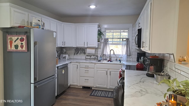 kitchen featuring sink, dark wood-type flooring, appliances with stainless steel finishes, white cabinetry, and light stone counters