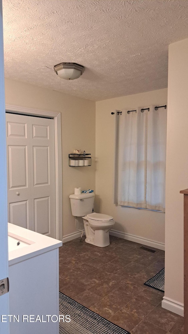 bathroom featuring vanity, a textured ceiling, and toilet