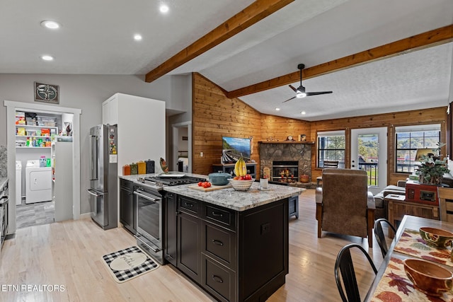 kitchen with vaulted ceiling with beams, light hardwood / wood-style flooring, stainless steel appliances, light stone countertops, and washer and dryer