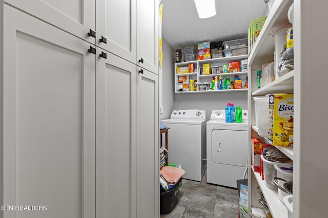 washroom with a textured ceiling, washing machine and dryer, and cabinets