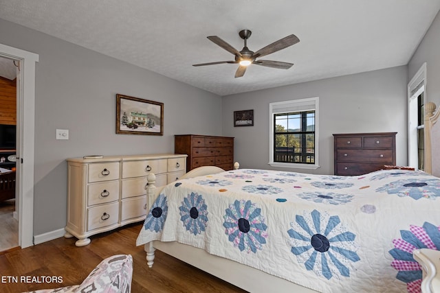 bedroom featuring dark wood-type flooring, a textured ceiling, and ceiling fan