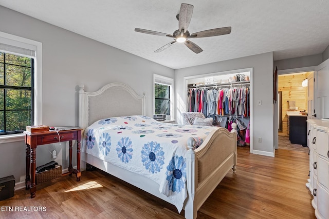 bedroom with multiple windows, hardwood / wood-style floors, and ceiling fan