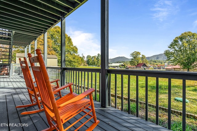 deck featuring a mountain view and a lawn