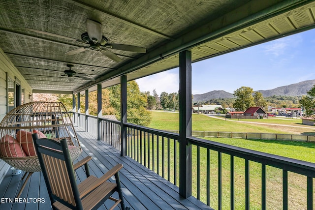 wooden deck featuring a yard, a mountain view, and ceiling fan