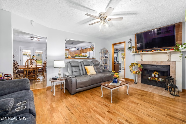 living room featuring hardwood / wood-style floors, a textured ceiling, a fireplace, and ceiling fan