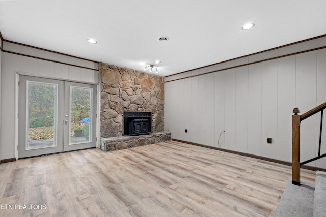 unfurnished living room featuring french doors, light hardwood / wood-style flooring, and a wood stove