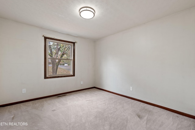 empty room featuring a textured ceiling and carpet