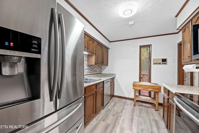 kitchen featuring decorative backsplash, crown molding, appliances with stainless steel finishes, a textured ceiling, and light hardwood / wood-style floors