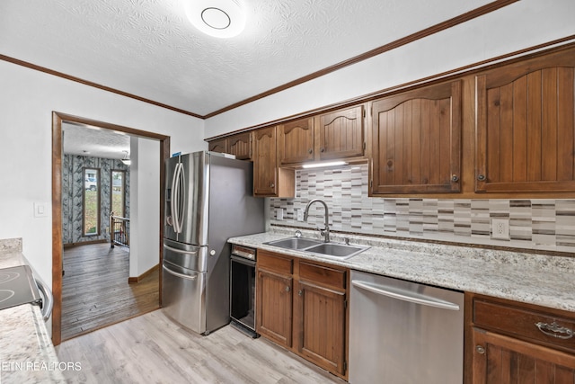 kitchen with stainless steel appliances, crown molding, sink, light wood-type flooring, and a textured ceiling