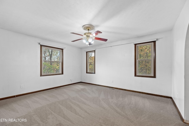 carpeted spare room with a textured ceiling, a healthy amount of sunlight, and ceiling fan