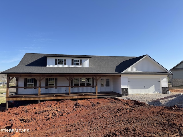 view of front facade with covered porch, an attached garage, and french doors