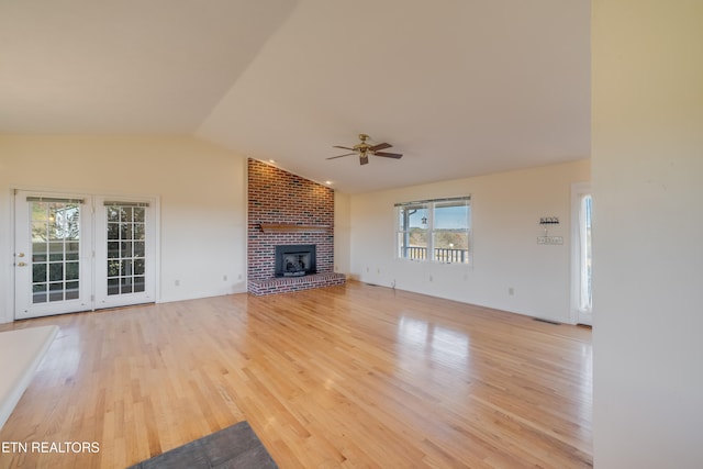 unfurnished living room featuring vaulted ceiling, a healthy amount of sunlight, light wood-type flooring, and ceiling fan