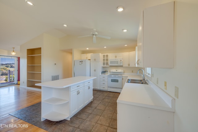 kitchen with white cabinets, dark hardwood / wood-style floors, a kitchen island, and white appliances