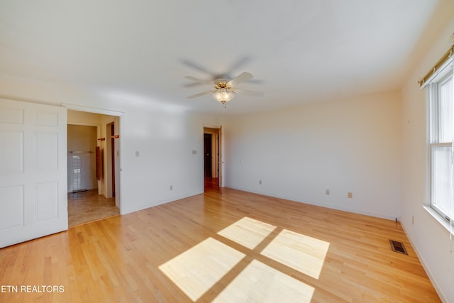 empty room with ceiling fan, hardwood / wood-style flooring, and plenty of natural light