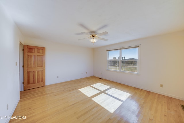 empty room with ceiling fan and light hardwood / wood-style flooring