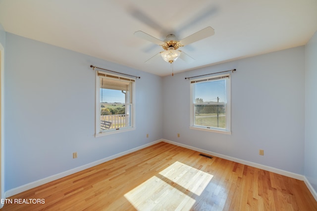 empty room with ceiling fan, light hardwood / wood-style flooring, and plenty of natural light