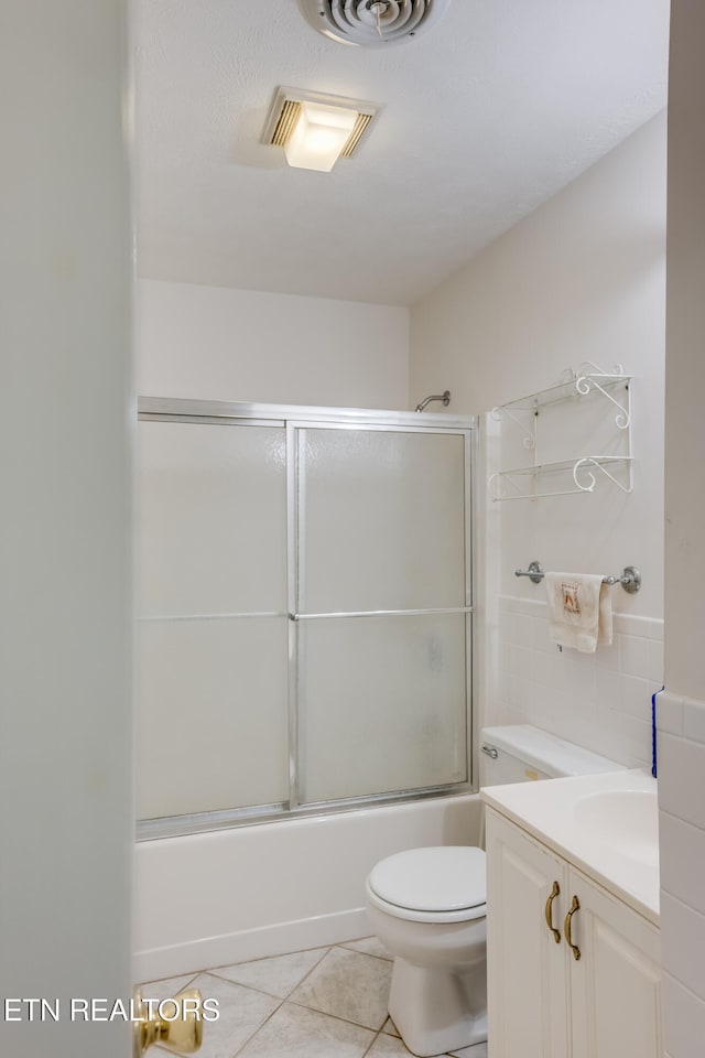 full bathroom with vanity, toilet, tile patterned flooring, and bath / shower combo with glass door