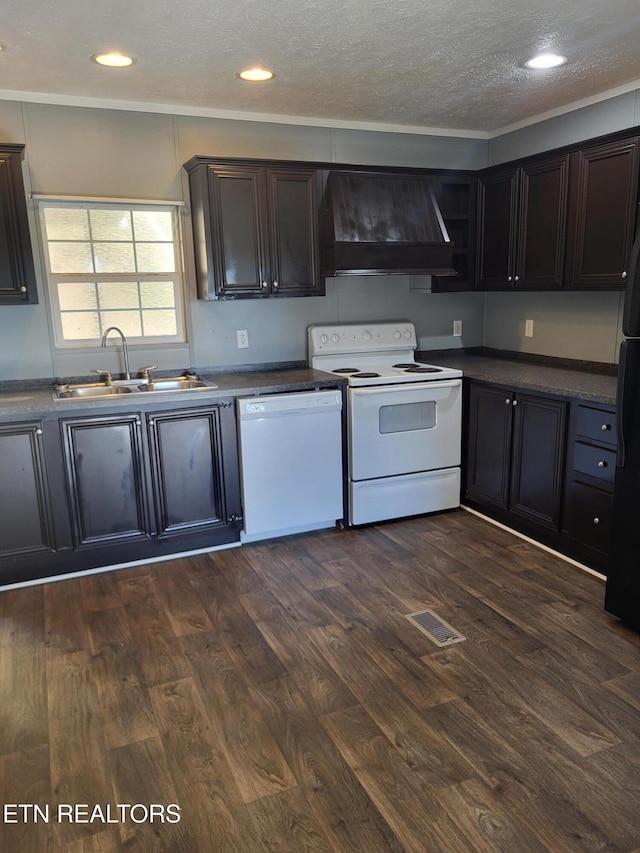 kitchen with dark wood-type flooring, custom range hood, sink, dark brown cabinetry, and white appliances