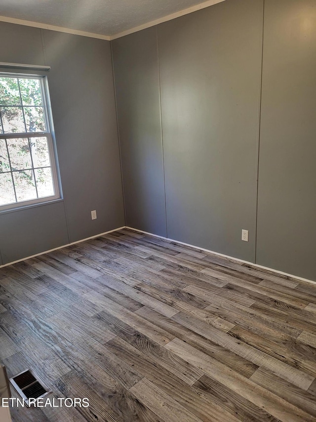 empty room with wood-type flooring and ornamental molding