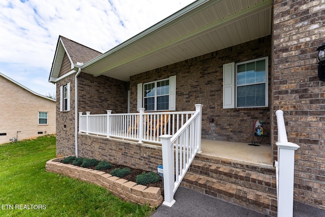 doorway to property with a porch and a lawn