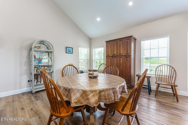 dining space featuring high vaulted ceiling and light wood-type flooring