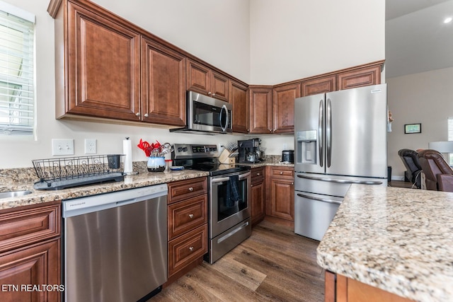 kitchen with light stone counters, dark wood-type flooring, and appliances with stainless steel finishes