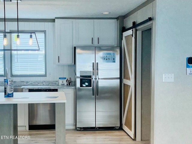 kitchen featuring stainless steel fridge with ice dispenser, light wood-type flooring, a barn door, and hanging light fixtures