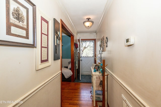 entryway with crown molding, dark wood-type flooring, and wainscoting