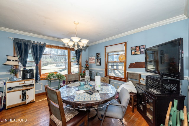 dining space featuring crown molding, wood finished floors, and a chandelier