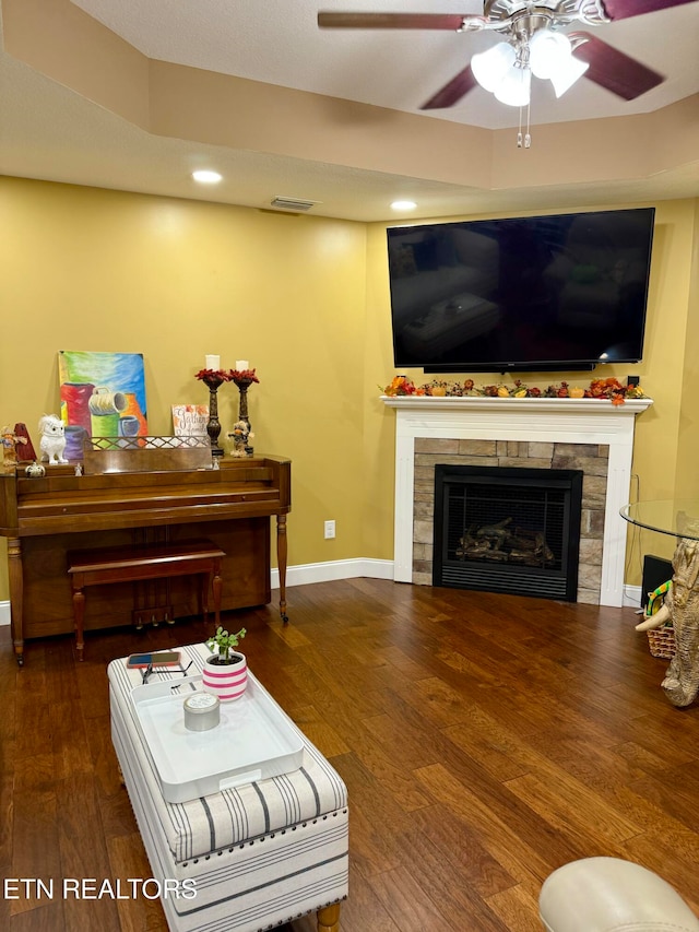 living room featuring ceiling fan, a fireplace, and dark hardwood / wood-style flooring