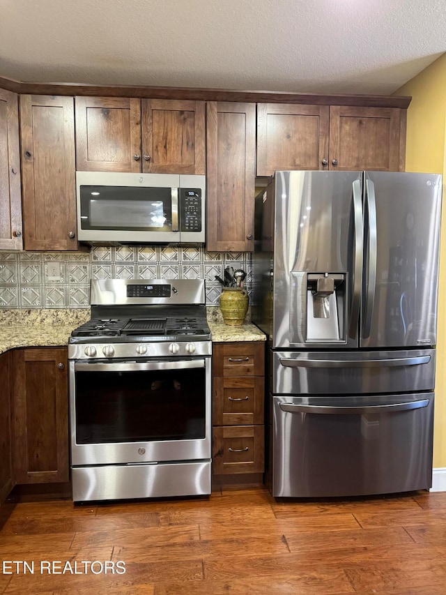 kitchen featuring appliances with stainless steel finishes, dark hardwood / wood-style floors, and light stone countertops