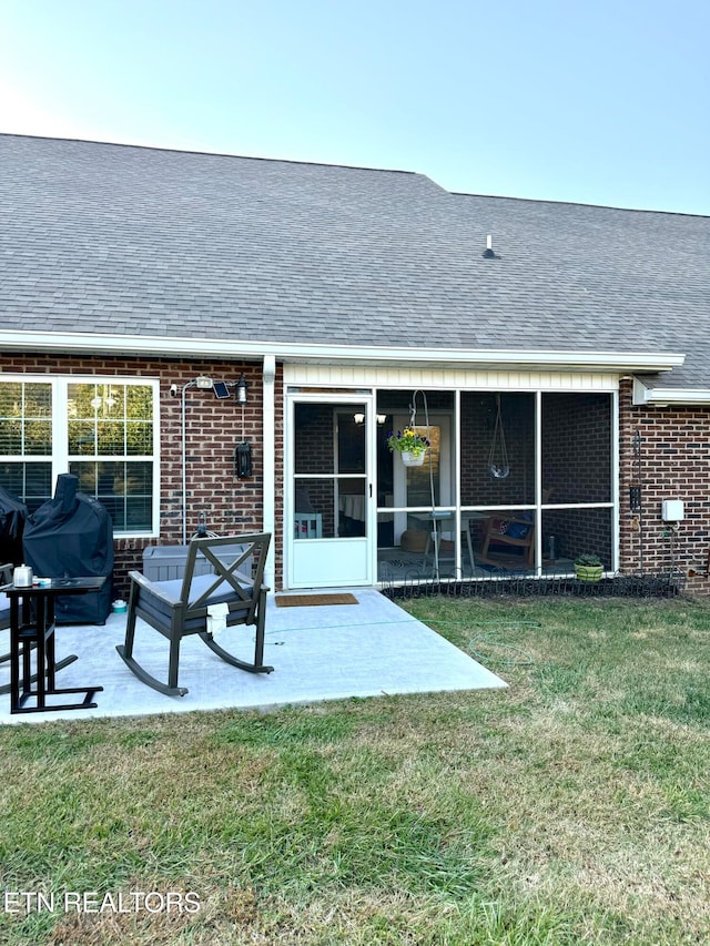 rear view of house with a yard, a patio area, and a sunroom