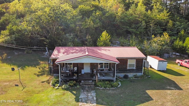 view of front facade with covered porch, a shed, and a front lawn