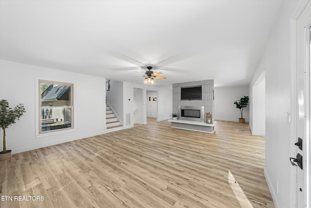 unfurnished living room with a fireplace, light wood-type flooring, and ceiling fan