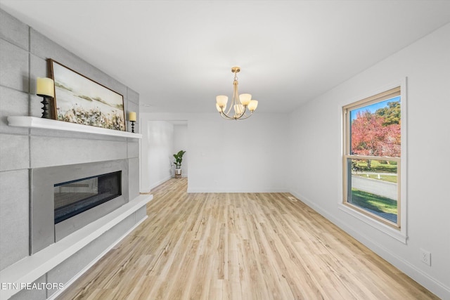 unfurnished living room with a notable chandelier and light wood-type flooring